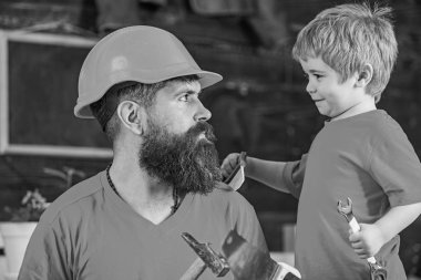 Baba, üst koruyucu kask okul atölyesinde farklı araçları kullanmak için küçük oğlu öğretim içinde sakallı. Babalık kavramı. Evlat, çocuk neşeli anahtar anahtarı, baba ile öğrenme kullanım araçları tutar