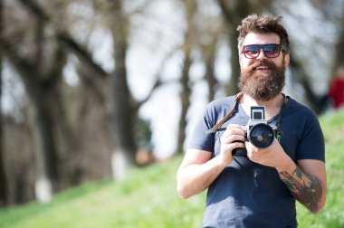 Fotoğraf çekimi ile meşgul uzun sakallı adam. Fotoğrafçı kavramı. Adam sakallı hippi fotoğrafçı tutun vintage fotoğraf makinesi. Sakal ve bıyık amatör fotoğrafçı doğa arka plan ile fotoğrafçı