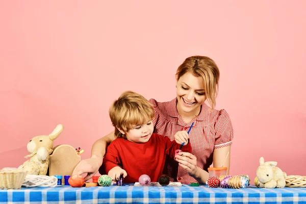 Easter and happy moments concept. Mother and son painting eggs