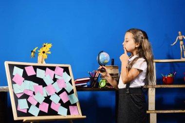 Düşünceli yüz ile kız öğrenci sınıfta dünya modeli tutar