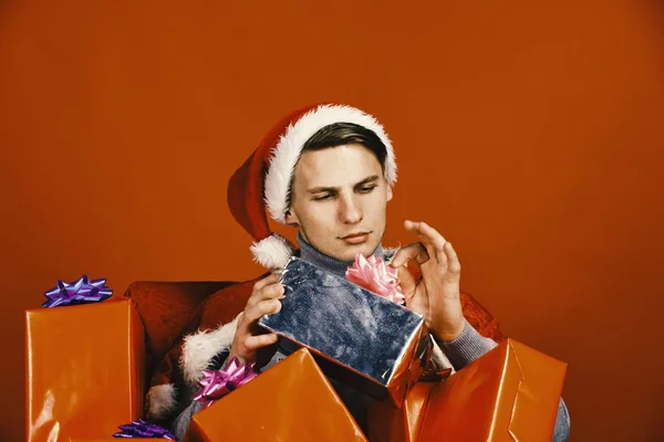 Muž drží dárky. Chlápek se zájmem se dívá na vánoční krabice — Stock fotografie