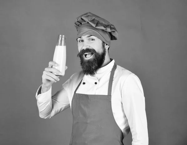 Cook med glada ansikte i vinröd uniform håller mjölk. — Stockfoto
