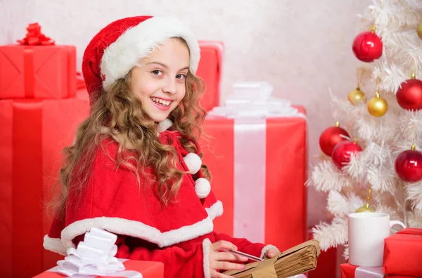 Carta para Santa. Lista de deseos. Niña niña sostener pluma y papel cerca del árbol de Navidad carta de escritura. Fui una buena chica todo el año. Niño escribe carta a Santa Claus. Niño traje de santa creer en el milagro —  Fotos de Stock