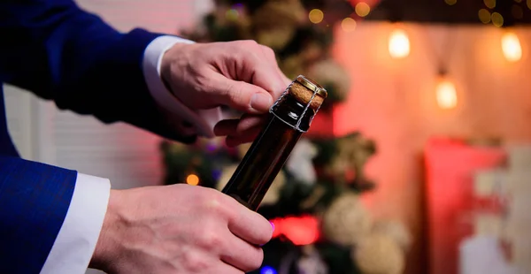 Mãos masculinas abrindo garrafa de champanhe no fundo decorações de Natal. Vamos comemorar. Abra o champanhe e celebre as férias. Celebre o Ano Novo com a bebida de champanhe. Brinde e saúde conceito — Fotografia de Stock