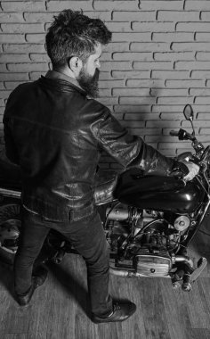 Sakallı, motorcu motorlu bisiklet garaj, tuğla duvar arka plan yakınındaki deri ceketli adam. Erkeksi hobi kavramı. Yenilikçi, vahşi Motorcu deri ceketli motosiklet üzerinde arka görüş oturur