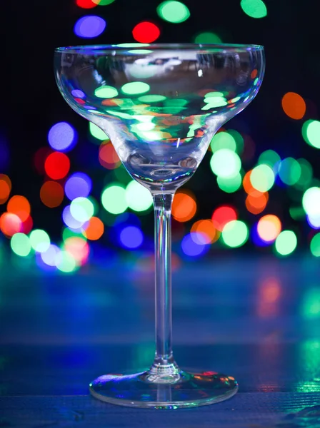 Qué beber en la fiesta de Navidad. Cóctel de alcohol para la fiesta de invierno. Concepto de ideas de cóctel. Recetas fáciles para bebidas alcohólicas de invierno. Copa de cóctel en luces coloridas guirnalda desenfocada —  Fotos de Stock