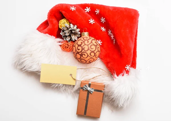 Silvestrovské a vánoční oslavu. Čepice Santa s Vánoční dárková krabička. Udržujte rodinné tradice. Pohled shora bílé pozadí Santa red hat. Vánoční dárky od santa. Atributy zimní dovolené — Stock fotografie