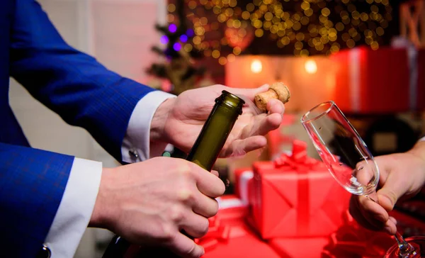 Hands opening champagne bottle and hold glass christmas decorations background. Cheers concept. Last minute before new year. Drink champagne or sparkling wine. Celebrate new year with champagne