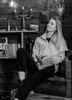 Kız öğrenci kitap ve mulled şarap ile rahatlatıcı. Bayan kareli giysiler içinde rüya gibi yüzünde rahat görünüyor. Gevşeme kavramı. Ahşap vintage iç kitap ile gündelik kıyafeti kız oturur