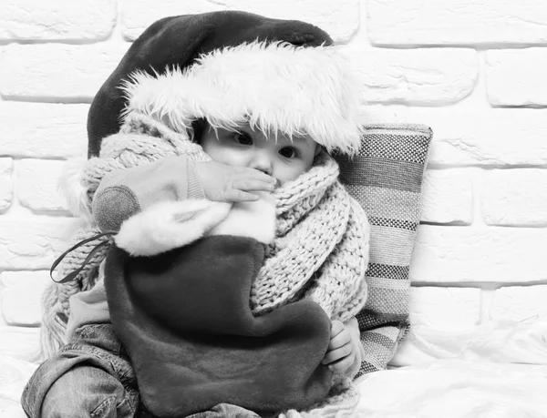 Petit garçon avec adorable curieux visage en pull rouge avec mannequin dans l'écharpe du chapeau de nouvelle année et Noël ou Noël bas ou bottes sur fond de mur de brique blanche — Photo