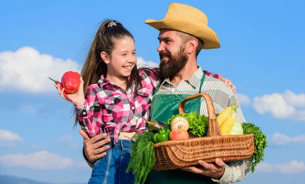 Gardening and harvesting. Family farm concept. Only organic and fresh harvest. Man bearded rustic farmer with kid. Farmer family homegrown harvest. Father and daughter hold basket harvest vegetables