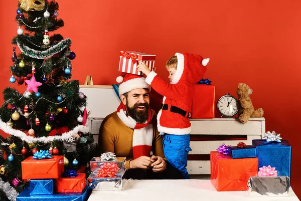 Weihnachtsfamilie öffnet Geschenke auf rotem Hintergrund. — Stockfoto