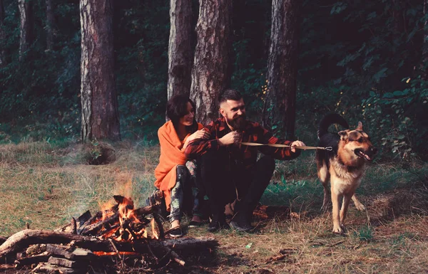 Paar mit Schäferhund am Lagerfeuer, — Stockfoto