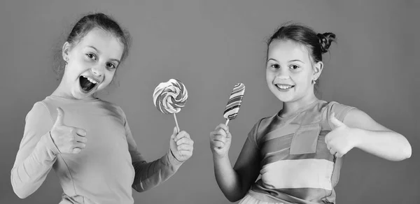 Los niños comen grandes caramelos dulces de colores. Hermanas con piruletas — Foto de Stock