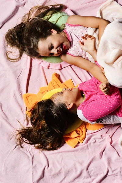 Meninas mentir sobre branco e rosa lençóis fundo cócegas — Fotografia de Stock