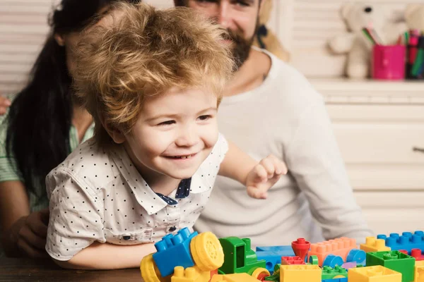 Parents watch their son play with colorful blocks. — Stock Photo, Image