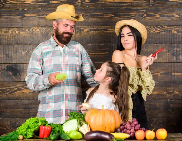 Family farmers with harvest wooden background. Parents and daughter celebrate autumn harvest festival. Family rustic style farmers at market with vegetables fruits and greenery. Family farm concept