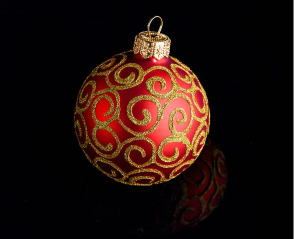 Ball ornament on black surface. Pick decor for christmas tree. Christmas ornament single red ball on black background. Christmas ornament concept. Elegant and luxury christmas decor close up