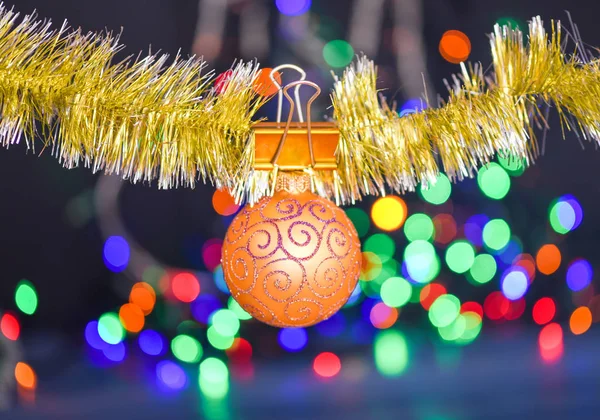 Christmas ornaments concept. Ball ornament hang on shimmering tinsel. Pick colorful decor for christmas tree. Tinsel with pinned christmas ornament on defocused garland lights background — Stock Photo, Image