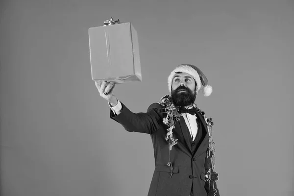 Man in smart suit, Santa hat and garlands on blue