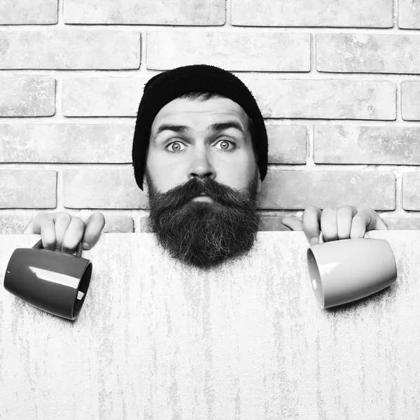 Barbudo brutal hipster caucásico con hoja de papel y tazas —  Fotos de Stock