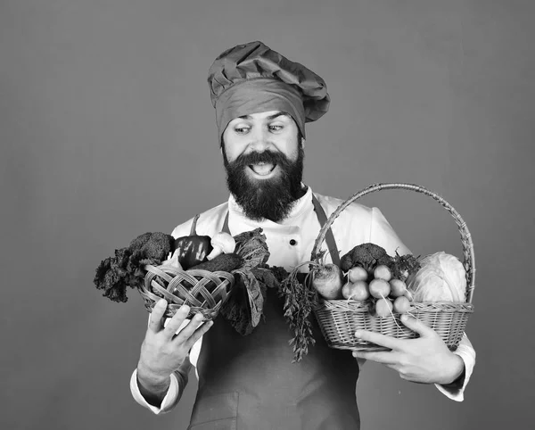 Кухар з щасливим обличчям в бордовій формі тримає овочі — стокове фото