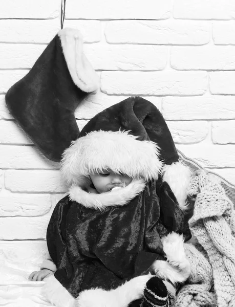 Küçük bebek çocuk kukla yeni yıl şapkası ve Noel veya Noel çorap veya beyaz tuğla duvar arka plan üstünde çizme ile kırmızı kazaklı sevimli merak yüz — Stok fotoğraf