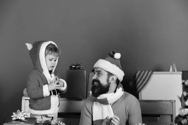 Kerstman en kleine assistent onder geschenkdozen. — Stockfoto