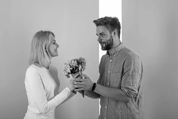 Чоловік вітає жінку з днем народження, пастельним фоном. Подарункова концепція. Чоловік дарує дівчині букет квітів. Подарунок на весілля з квітами. Пара закоханих святкує свято — стокове фото