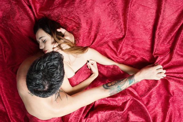 Man met tatoeages houdt vrij slapende dame in armen — Stockfoto