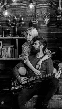 Bayan ve rüya gibi yüzleri sakallı hugs ve gitar çalıyor. Romantik akşam kavramı. Aşık çift sıcak atmosferde romantik akşamın. Çift ahşap vintage iç gitar müziğin keyfini çıkarın