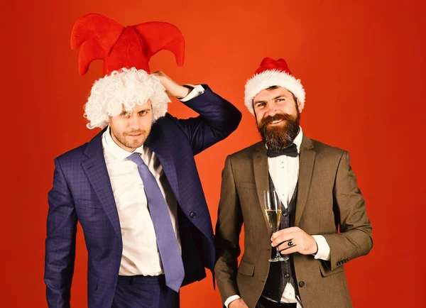 Men in smart suits, Santa and jester hats on red