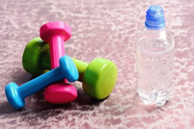 Plastik su şişesi Bordo arka plan üzerinde yakınındaki halter