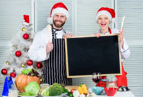 Man and woman chef santa hat near christmas tree hold blackboard copy space. Christmas recipe concept. Cooking christmas meal. Family traditional menu for christmas dinner. Menu for our family