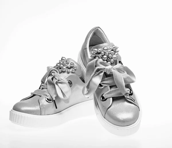 Footwear for girls and women decorated with pearl beads. Pair of pale pink female sneakers with velvet ribbons. Trendy sneakers concept. Cute shoes isolated on white background — Stock Photo, Image