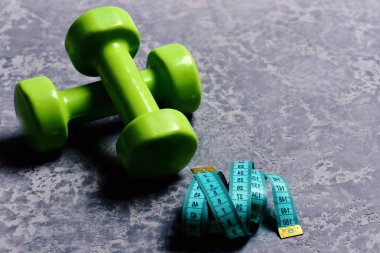 Egzersiz ve ölçüm kavramı. Ölçüm bandı rulo plastik Barbell yakınındaki.