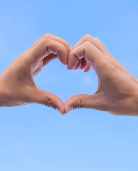 Manos juntas en forma de corazón fondo cielo azul. Concepto de símbolo de amor. El gesto del corazón de la mano forma usando los dedos. Manos masculinas en forma de corazón símbolo de amor y romance —  Fotos de Stock