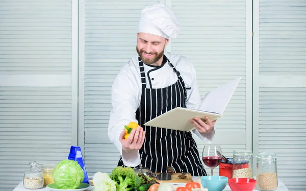 Boka familjerecept. Enligt receptet. En skäggig kock som lagar mat. Killen läste bokrecept. Kulinarisk konst koncept. Människan lär sig recept. Förbättra matlagning skicklighet. Ultimat matlagningsguide för nybörjare — Stockfoto