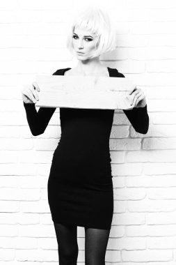 sevimli seksi kız veya moda makyaj pembe peruk memnun yüzünde güzel bir kadınla ve siyah elbise vintage ahşap tahtası beyaz tuğla duvar arka planda tutan derin yaka ile oldukça, girintili kopyalama