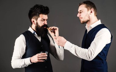 Arkadaş, iş ortağı, asistanı sakal lambası yakan adama yardım ediyor..