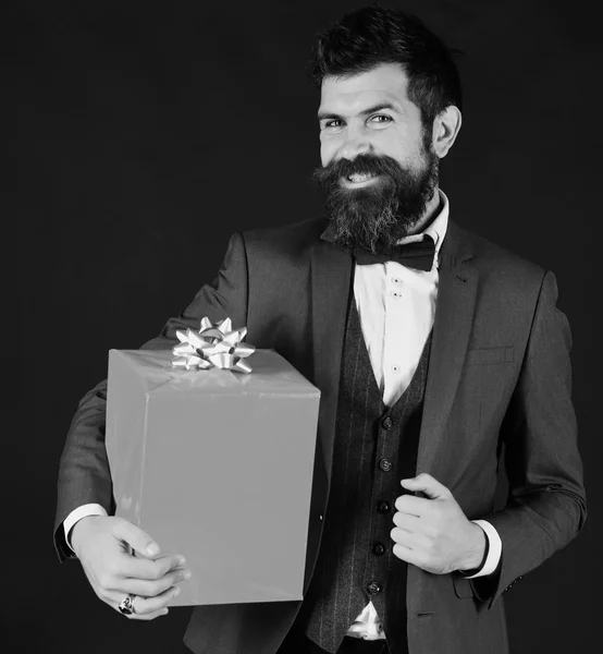 Gülümseyen yüzü ve kırmızı hediye kutusu olan bir iş adamı. — Stok fotoğraf