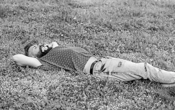 Ein bärtiger Mann mit Löwenzahnblüten im Bart lag auf einer Wiese, Grashintergrund. Frühlingskonzept. Mann mit Bart im schlafenden Gesicht genießt den Frühling. Hipster mit Löwenzahnstrauß im Bart entspannend — Stockfoto