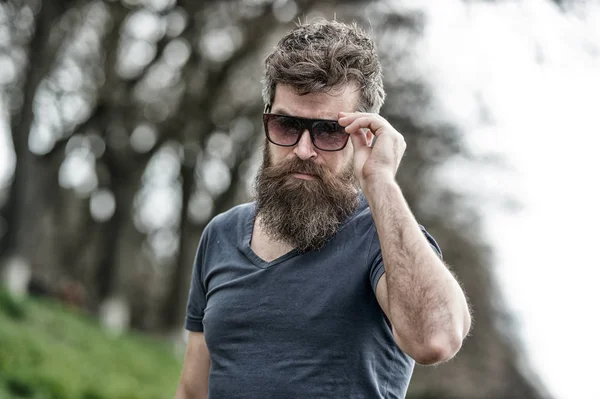 Macho barbu hipster brutal. Concept de coiffeur. Homme barbu avec moustache visage sérieux fond de nature confiant. Homme barbu avec des lunettes de soleil. Hipster barbu confiant dans les lunettes de soleil à la mode sombre — Photo