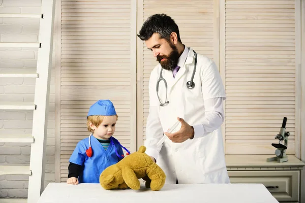 Hombre con barba y niño sostienen jeringa sobre fondo de madera. — Foto de Stock