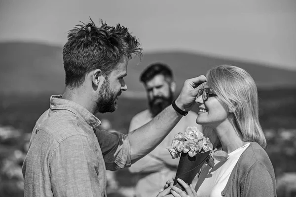 Paar verliefd daten terwijl jaloerse echtgenoot aankeek kijken op de achtergrond. Onbeantwoorde liefde concept. Liefhebbers vergadering buiten flirt romantiek betrekkingen. Paar romantische datum minnaar aanwezig boeket bloemen — Stockfoto