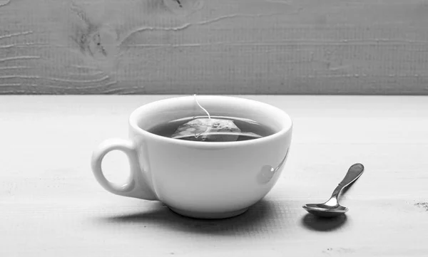 Mug filled with boiling water, teabag and spoon on white background. Mug filled with hot water and dipped bag of black tea. Process of black tea brewing in ceramic mug. Tea brew concept — Stock Photo, Image