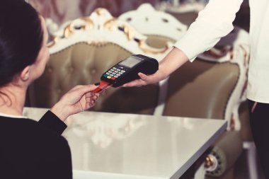 Nakitsiz ödemeler için kredi kartı terminali. Kasiyer kart okuyucu tutuyor