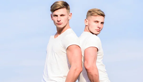 Men twins brothers muscular guys in white shirts sky background. Brotherhood concept. Benefits of having twin brother. Friendship of brothers. Benefits and drawbacks of having identical twin brother