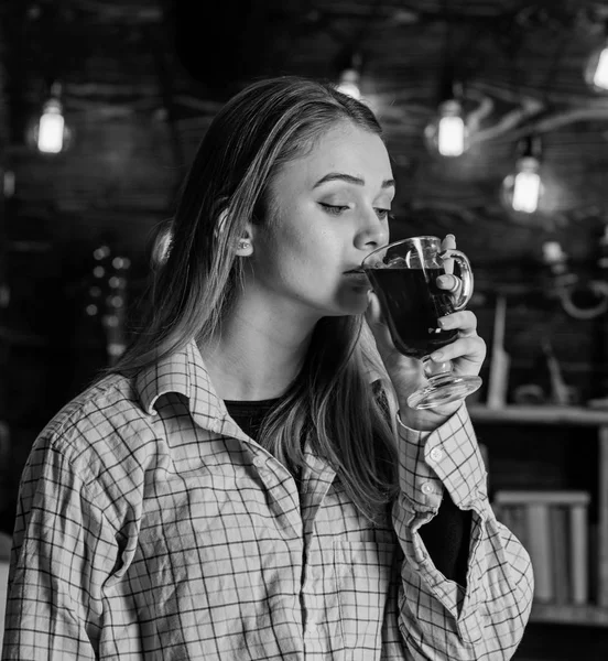 Lady enjoy mulled wine in warm atmosphere, wooden interior. Girl on relaxed face in plaid clothes relaxing, close up. Rest and relax concept. Girl relaxing and drinking mulled wine