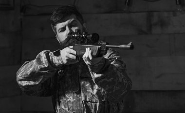 Sakallı kamuflaj elbiseler, ahşap iç arka plan giyer. Maço gamekeepers evinde sıkı yüzünde. Avcı kavramı. Hunter, avcılık, kopya alanı daha önce silah nişan ile acımasız hipster